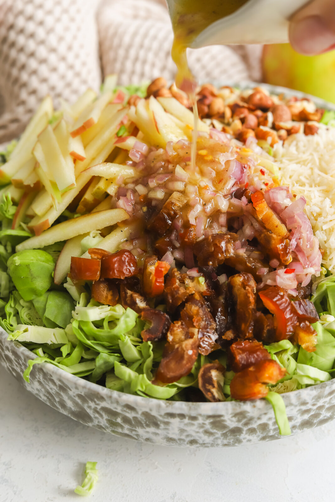 close up of dressing being poured on salad