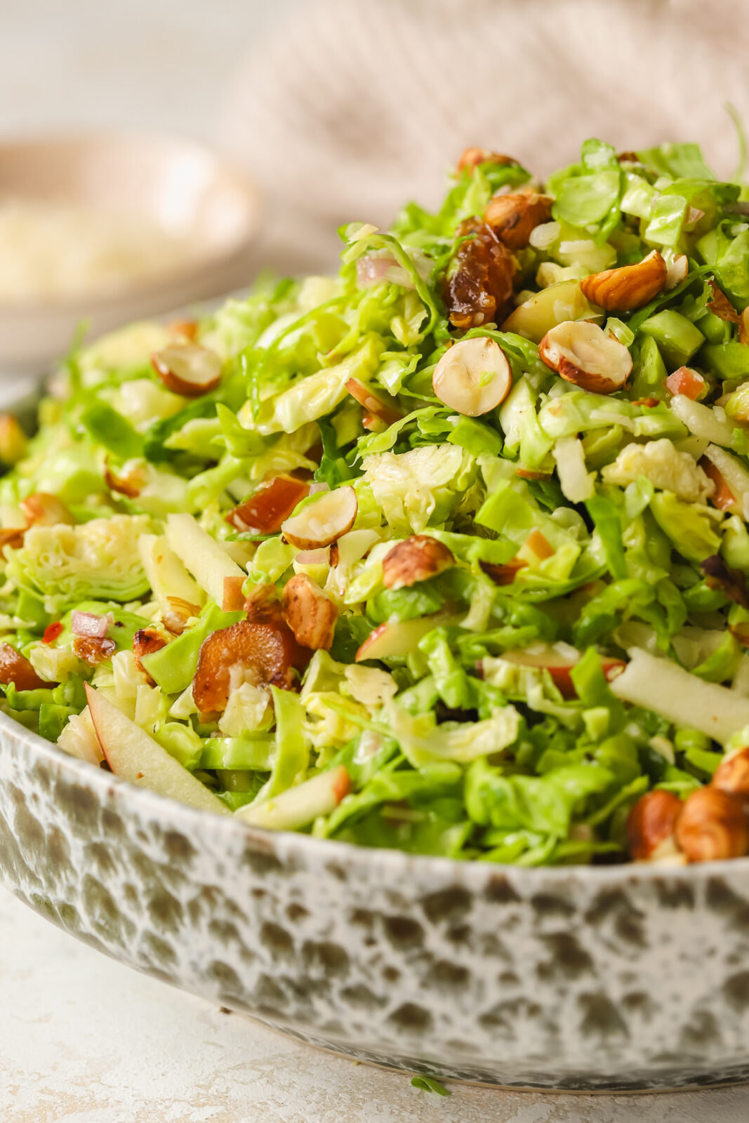 side angle of brussels sprouts salad in a bowl with hazelnuts, dates and apples