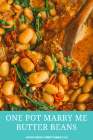 wooden spoon in a pot of cooked butter beans and sundried tomato sauce