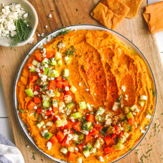 spicy buffalo hummus on a plate with garnishes