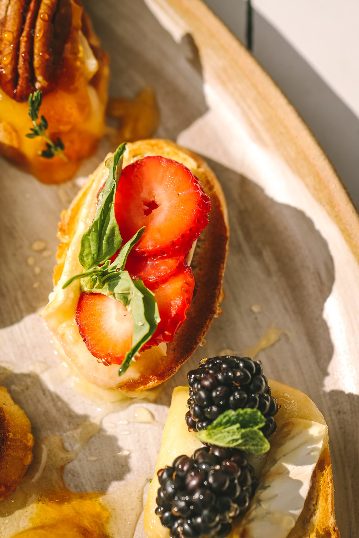 side angle close-up of strawberry slices and brie on a crostini