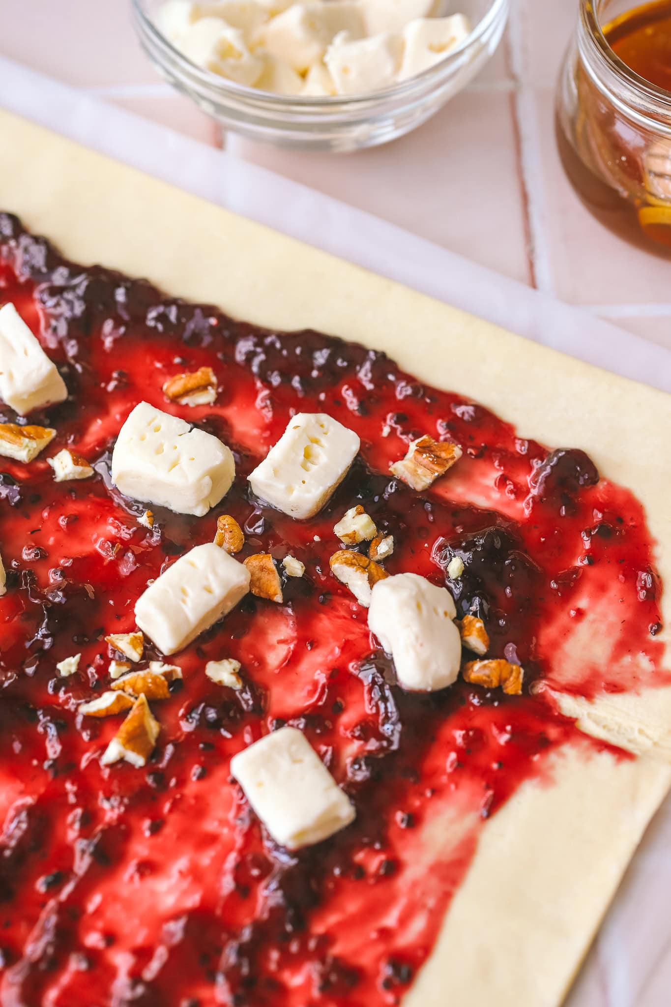 close up of puff pastry dough with jam, brie and pecans