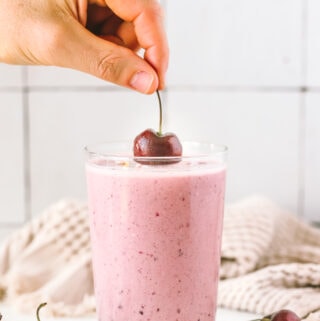 hand placing a cherry on top of the smoothie