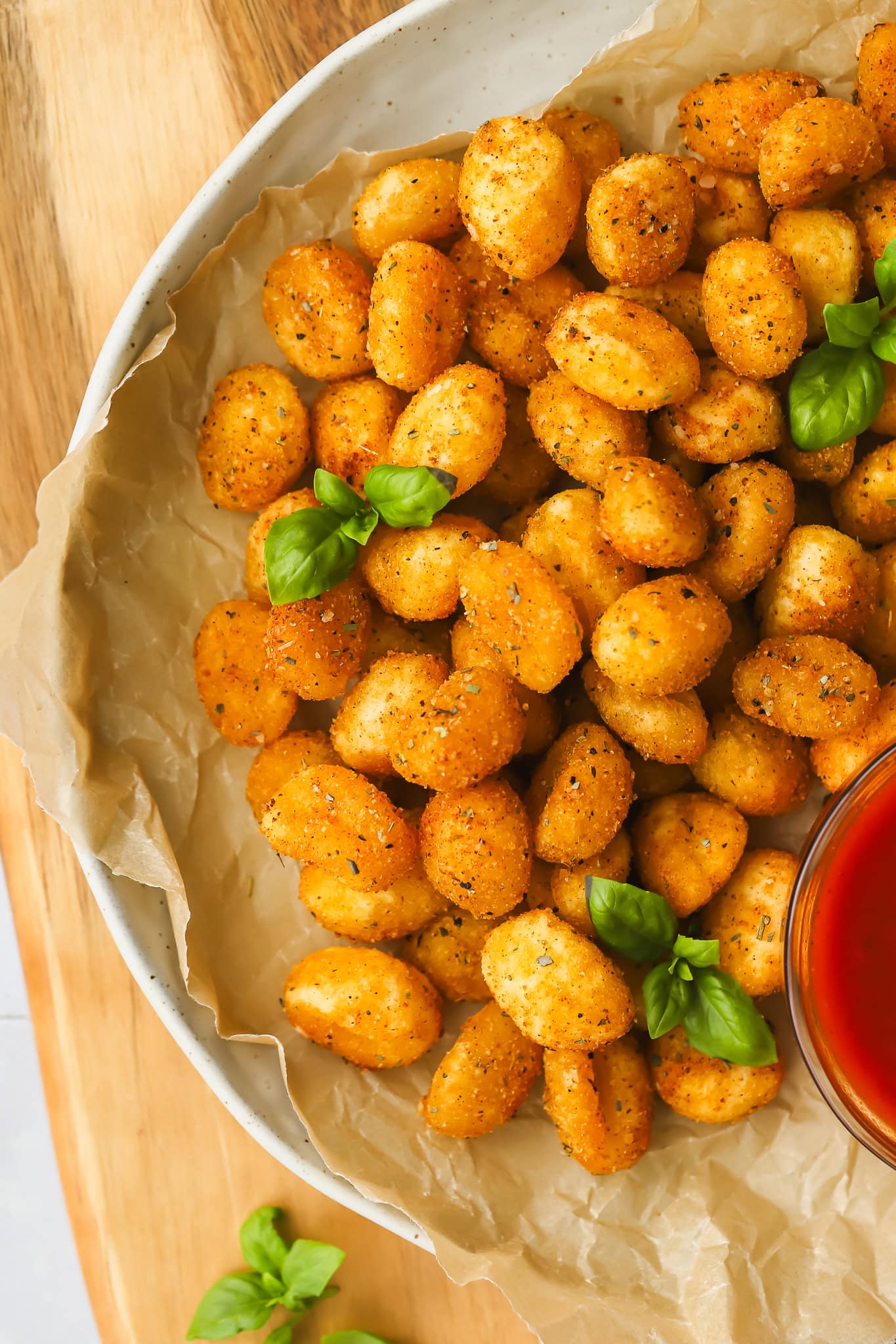 air fried gnocchi with basil garnish in a serving dish