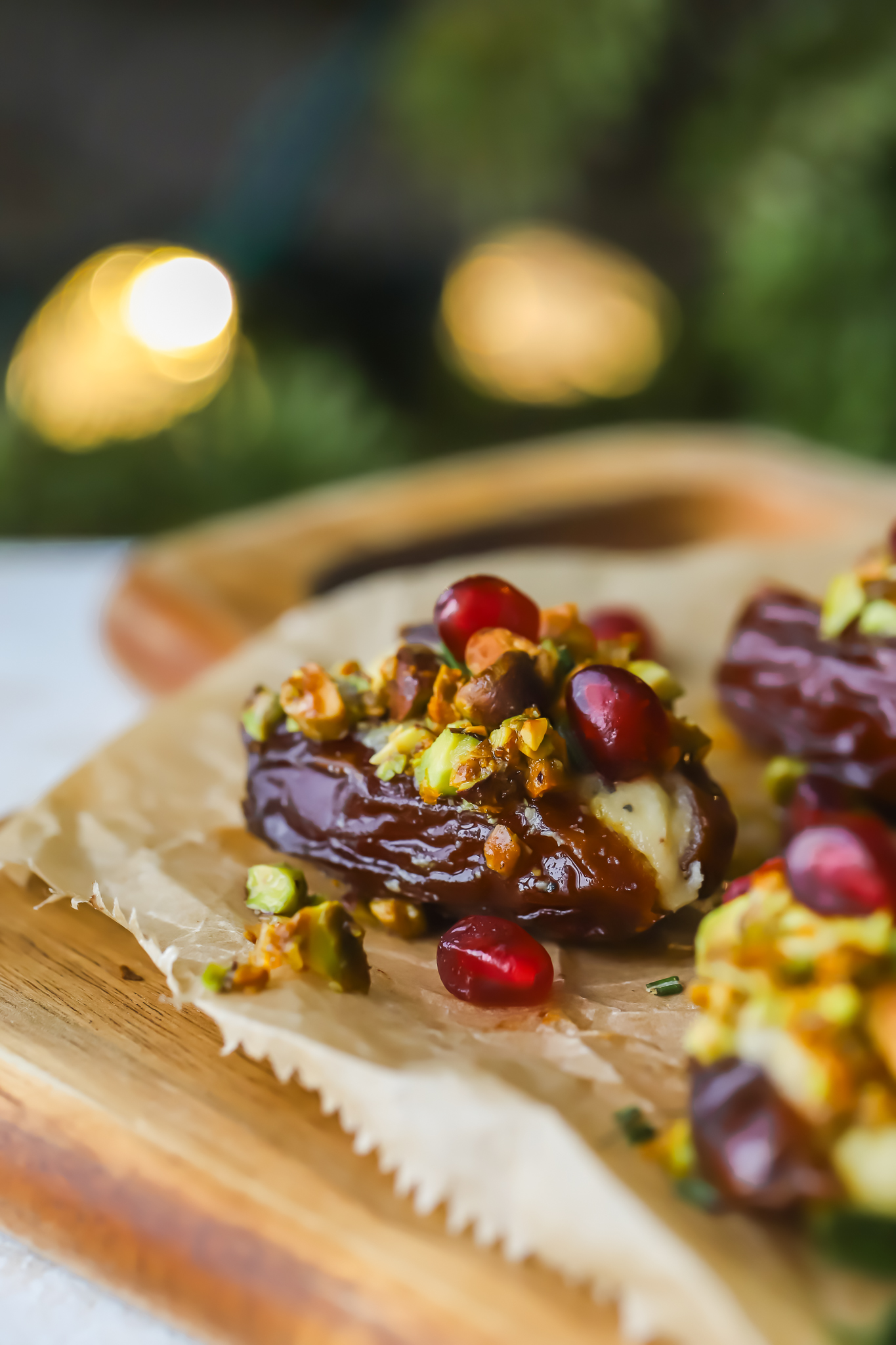 stuffed date on a serving tray with pistachios and pomegranate seeds