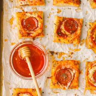 hot honey in a bowl with pepperoni pizza tarts on a tray