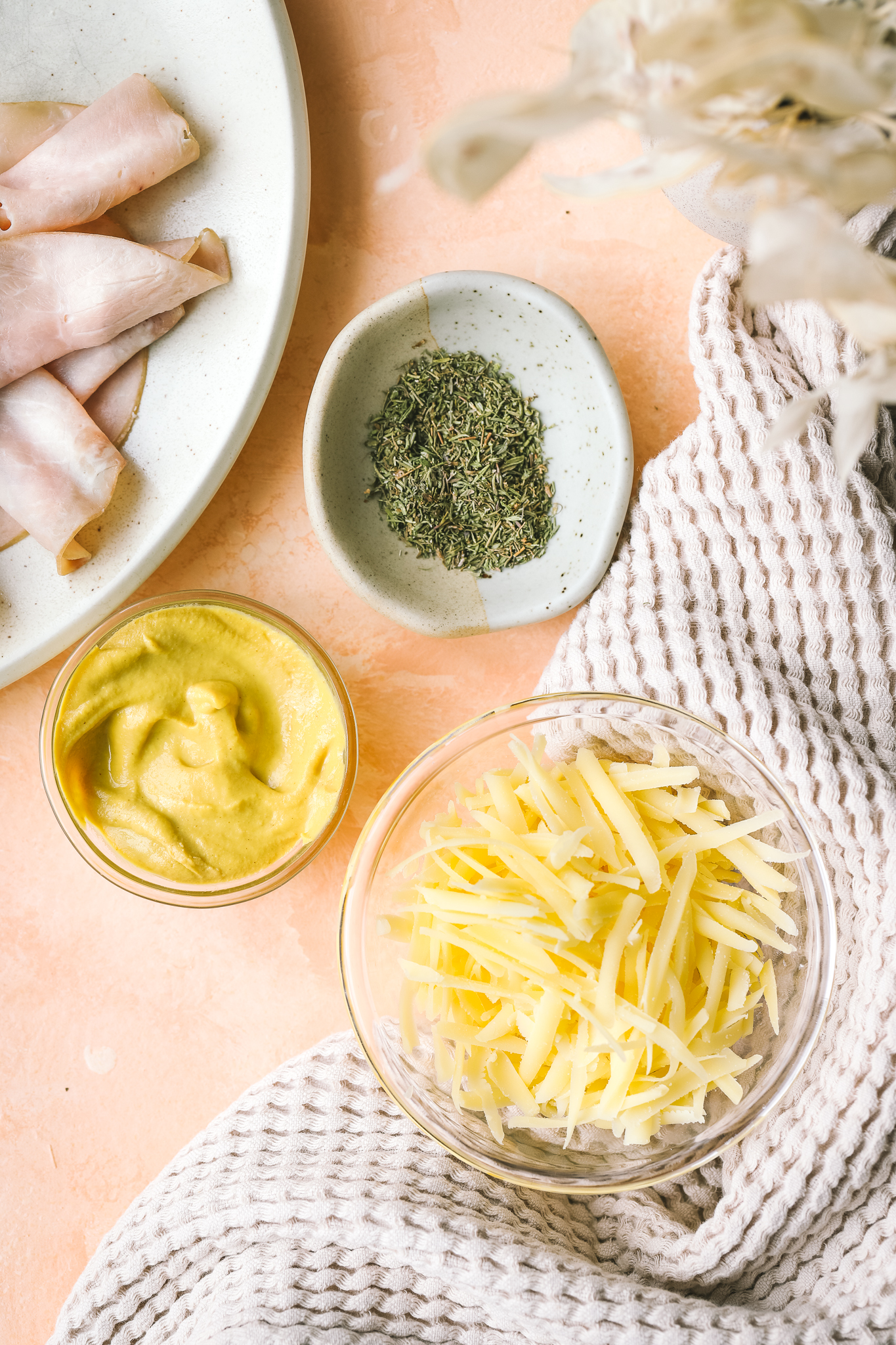 mustard in a bowl, grated Gruyere cheese in a bowl, ham on a plate and dried thyme in a bowl