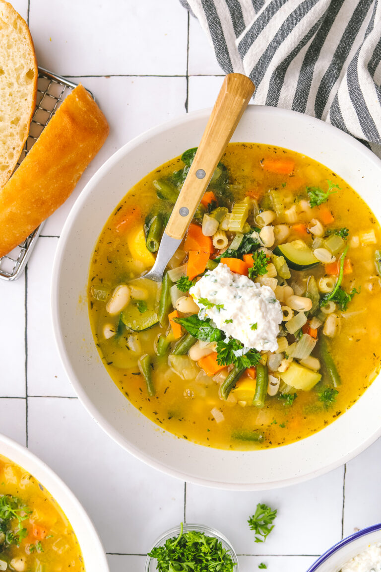 Spring minestrone soup in a bowl topped with basil-lemon ricotta