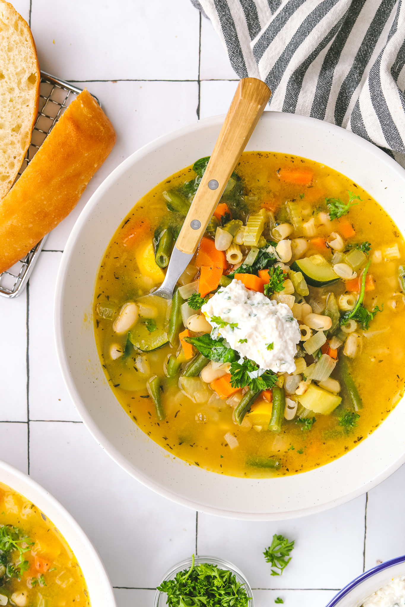 Spring minestrone soup in a bowl topped with basil-lemon ricotta