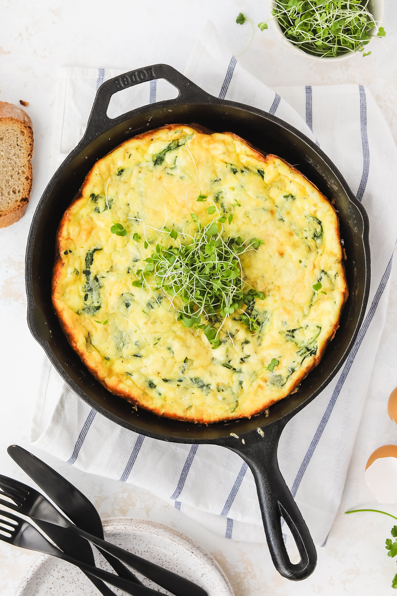 Spring frittata in a pan topped with fresh herbs