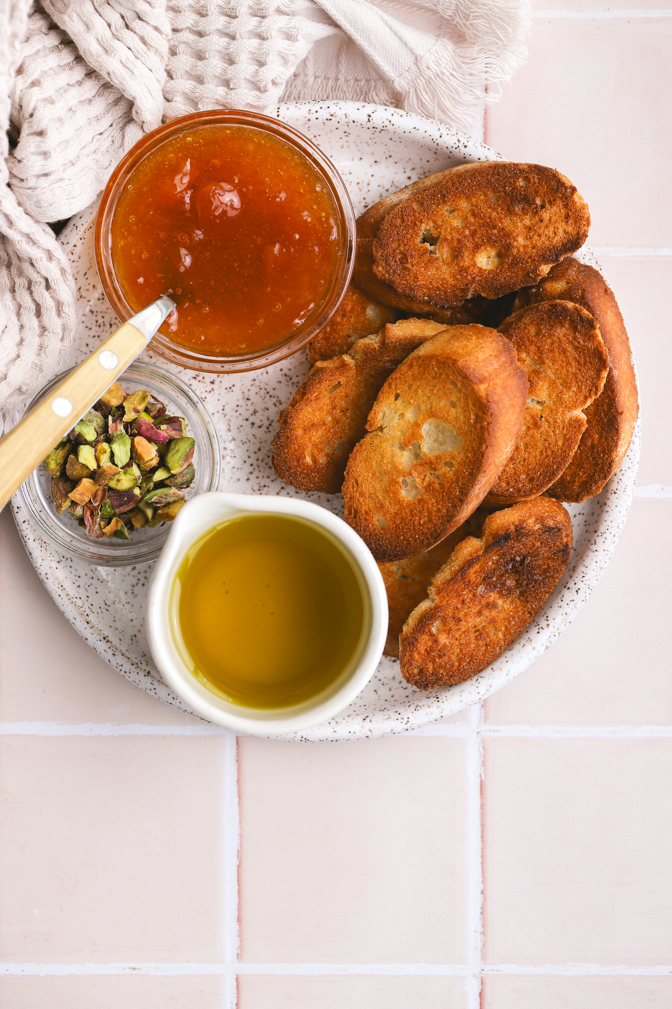 crostini, pistachios, olive oil and apricot jam on a plate