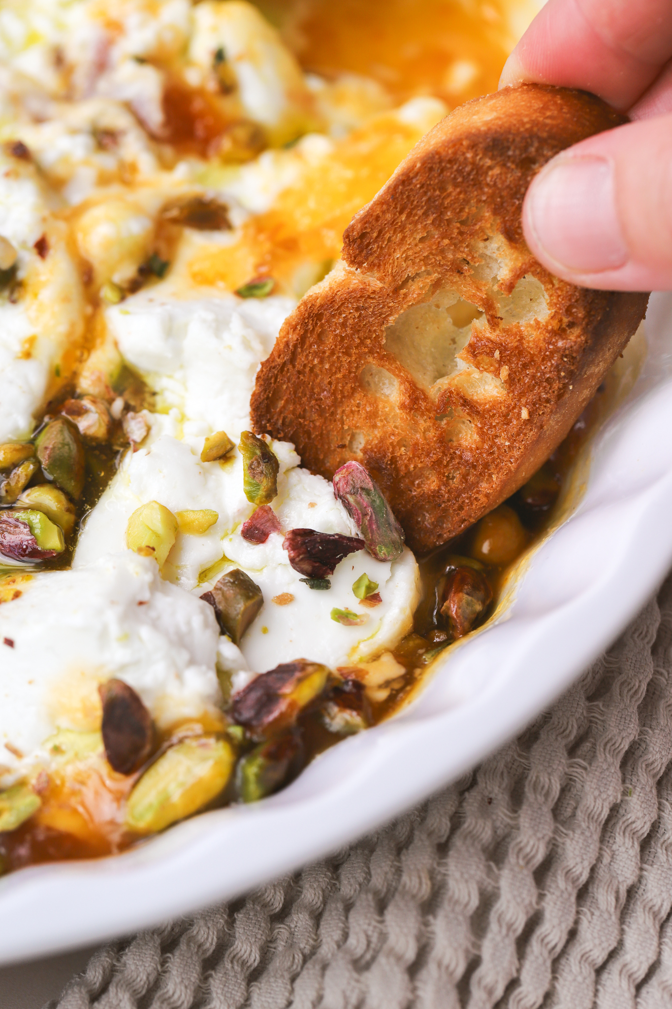 crostini dipped into baked goat cheese