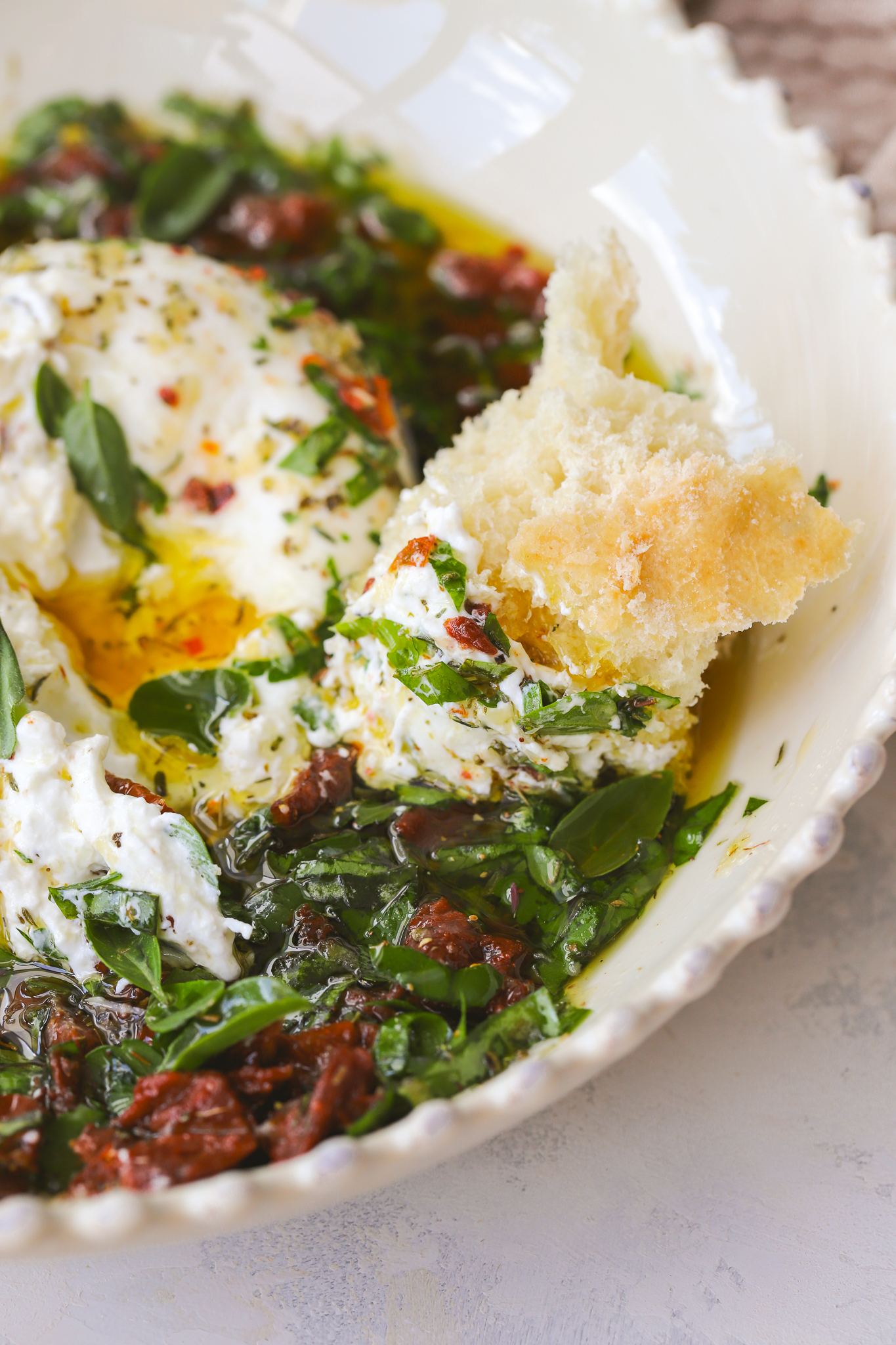 bread dipped into burrata and olive oil with herbs