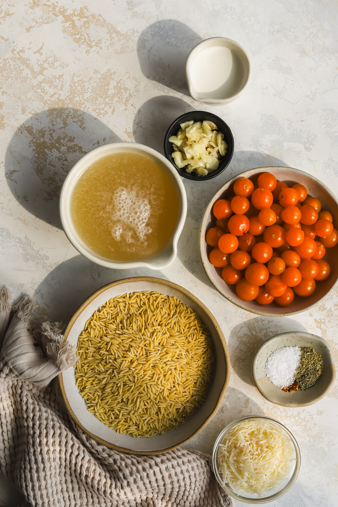 orzo, tomatoes, garlic, broth and parmesan cheese in bowls