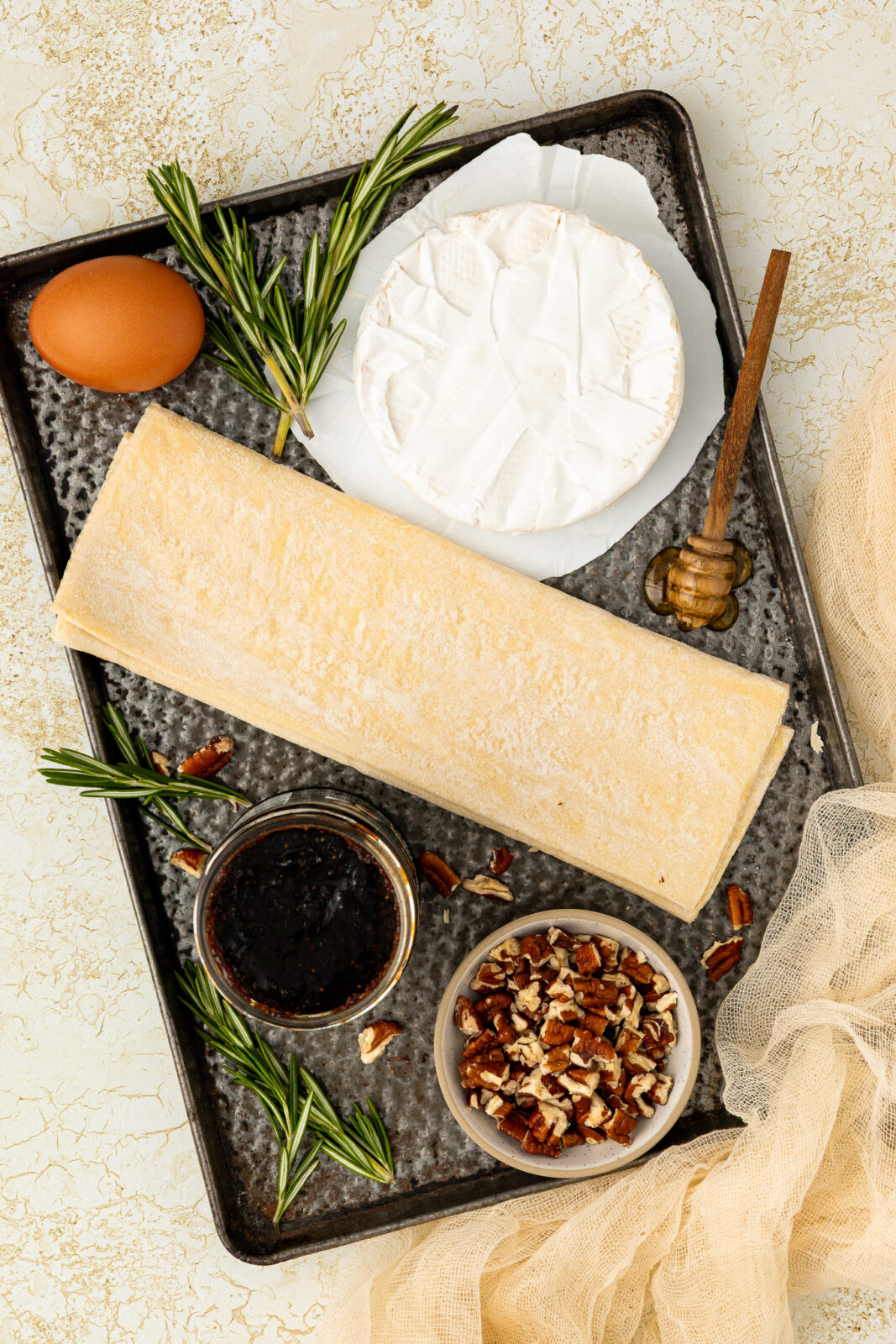 brie cheese, puff pastry, fig jam, pecans on a baking sheet