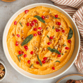 pumpkin whipped feta topped with pomegranate seeds, walnuts and sage in a bowl