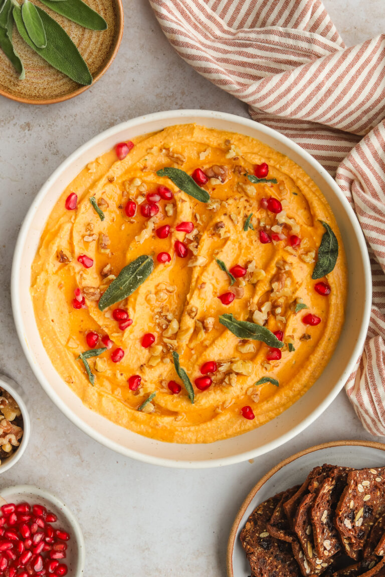 pumpkin whipped feta topped with pomegranate seeds, walnuts and sage in a bowl