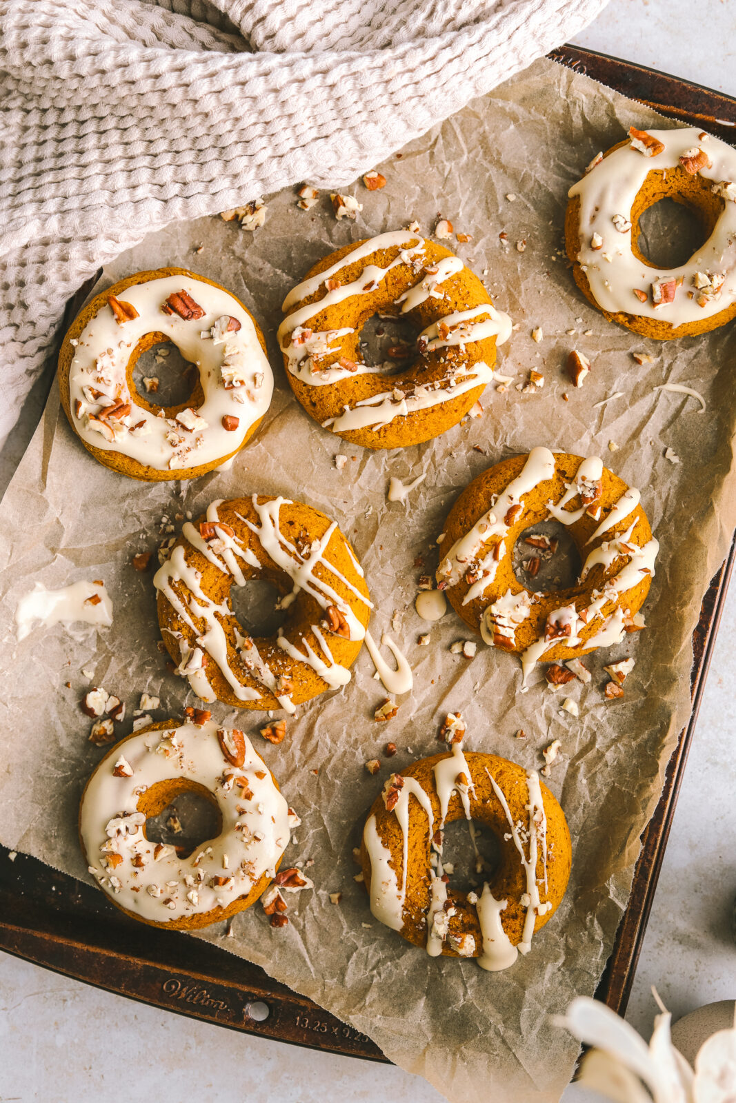 iced pumpkin donuts on a baking sheet