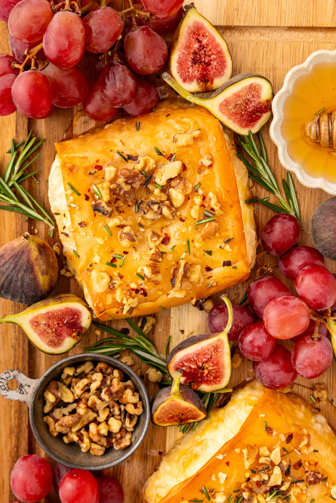 overhead of baked feta on a serving board with grapes and figs