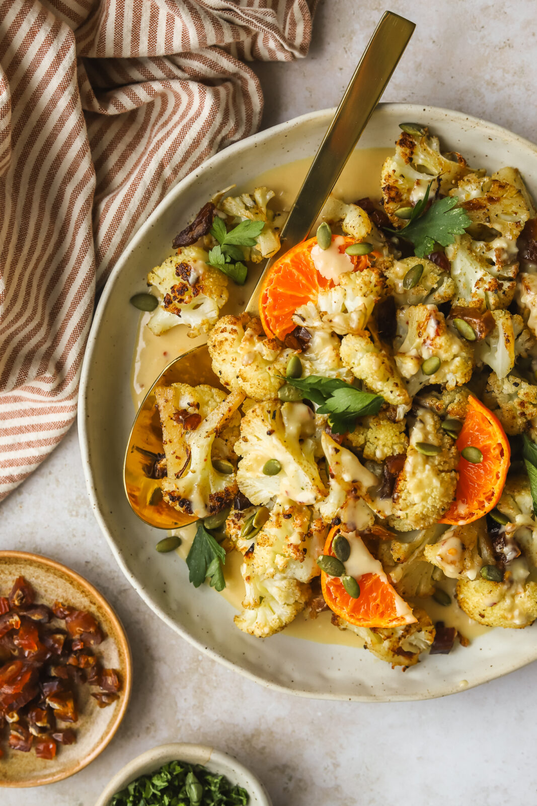 roasted cauliflower in a serving dish with orange tahini sauce