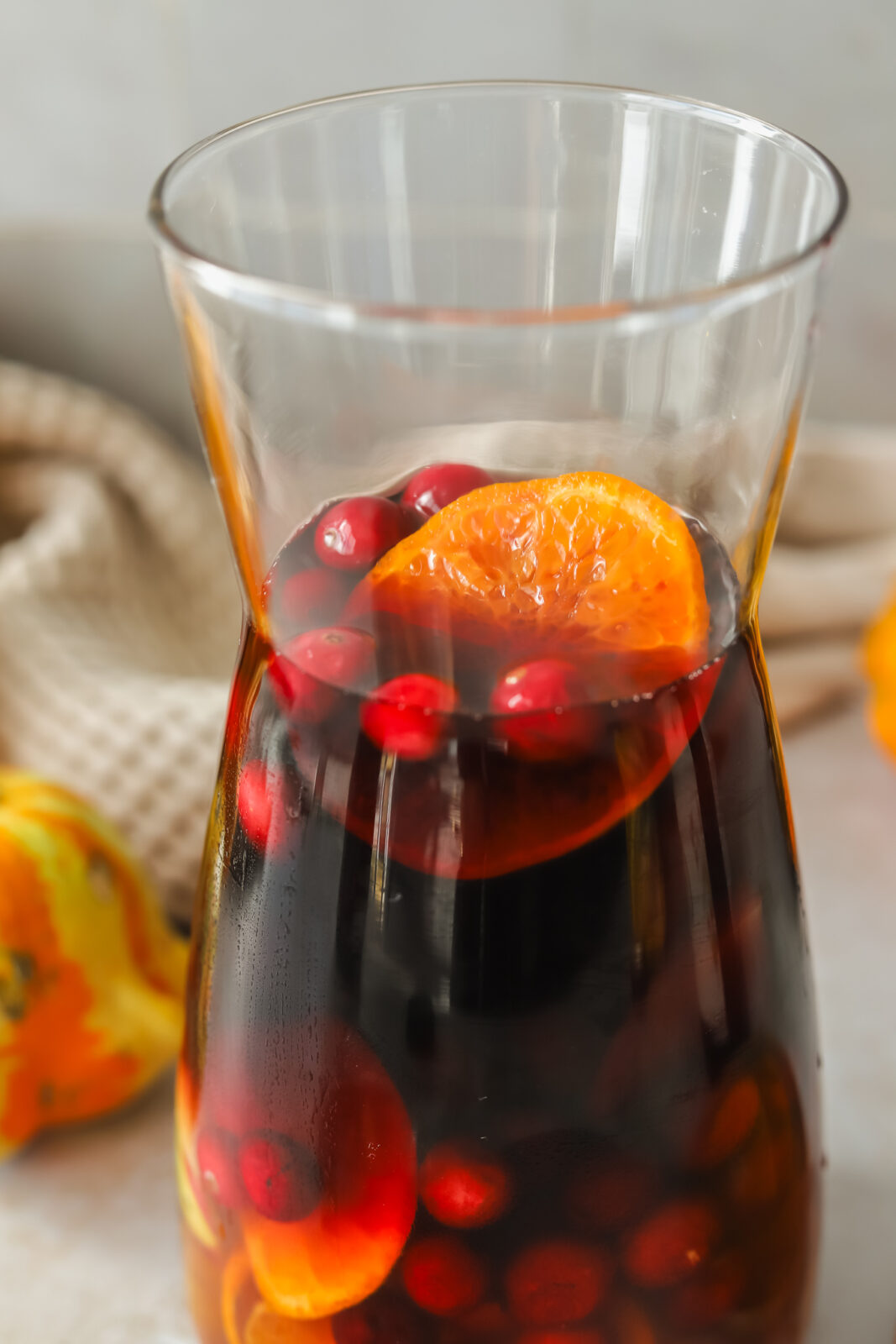 close-up of orange slices and cranberries in a pitcher of red sangria