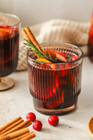 glass of red sangria with oranges, apples, cinnamon stick and rosemary