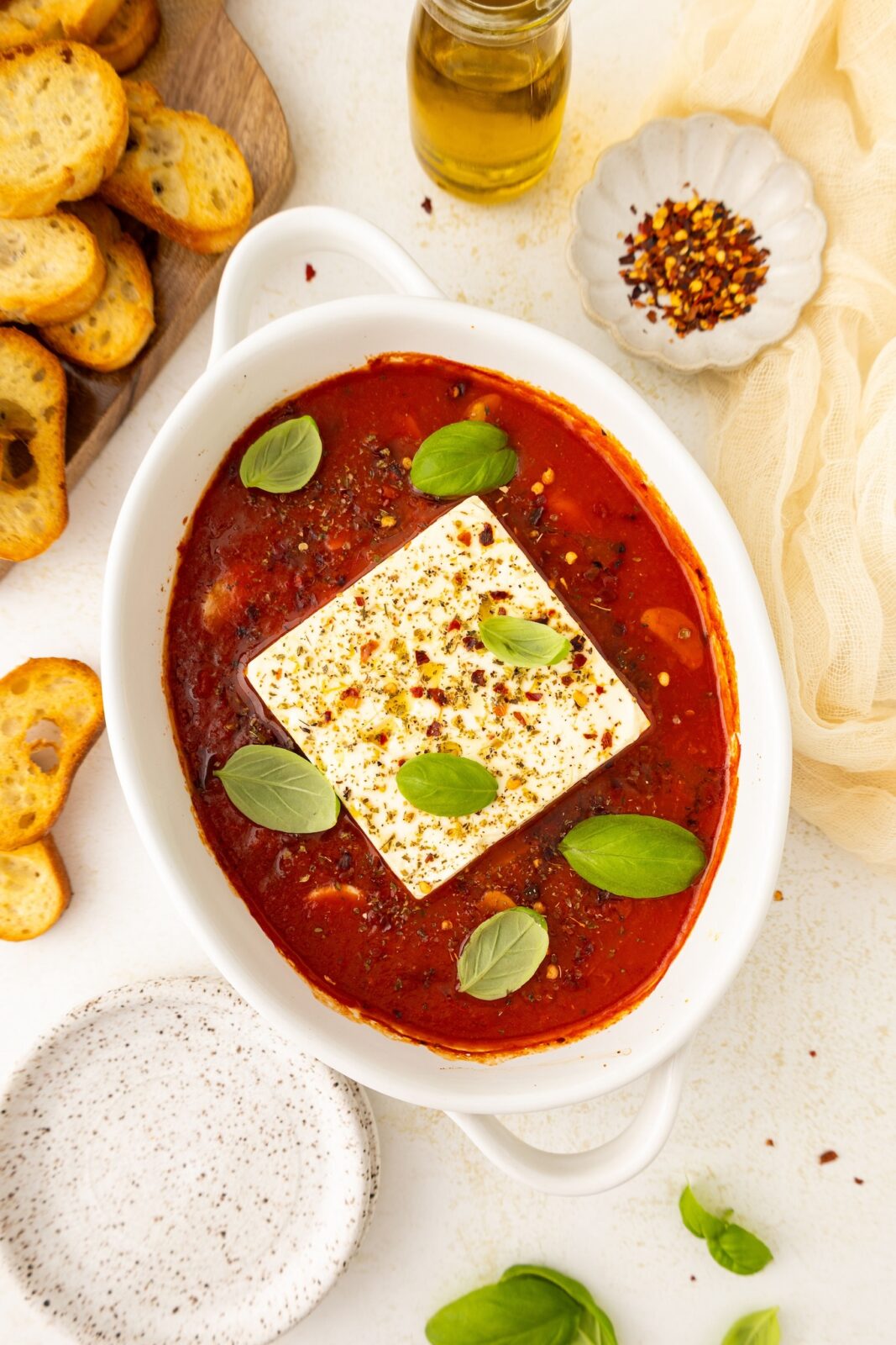 a piece of feta cheese in marinara sauce with fresh herbs