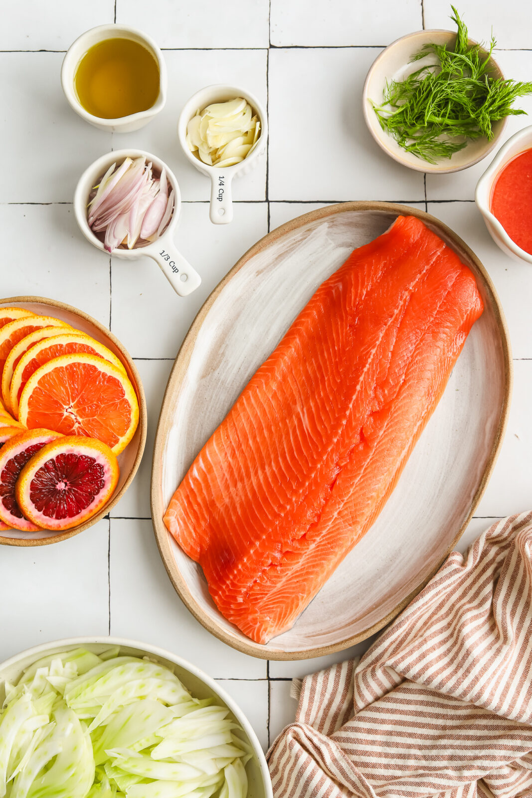 salmon on a platter, citrus slices in a bowl, fennel slices in a bowl